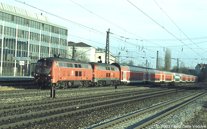 218 440-6 in orientrot und 218 442-2 in verkehrsrot donnern mit ihren acht Doppelstockwagen als RE 31430 (Mühldorf (Obb.) 15:37 - München Hbf 17:32) durch den Heimeranplatz (München, Frühling 2002).