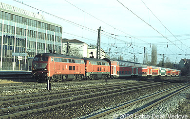 218 440-6 in orientrot und 218 442-2 in verkehrsrot donnern mit ihren acht Doppelstockwagen als RE 31430 (Mühldorf (Obb.) 15:37 - München Hbf 17:32) durch den Heimeranplatz (München, Frühling 2002).